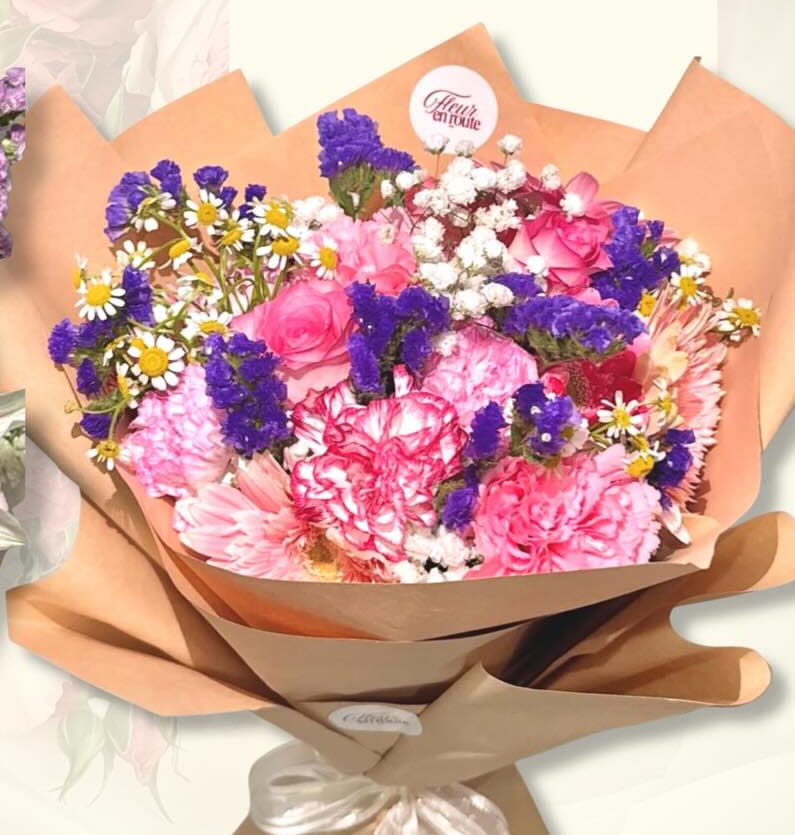 Kraft-wrapped bouquet of pink carnations and roses with violet statice and chamomile