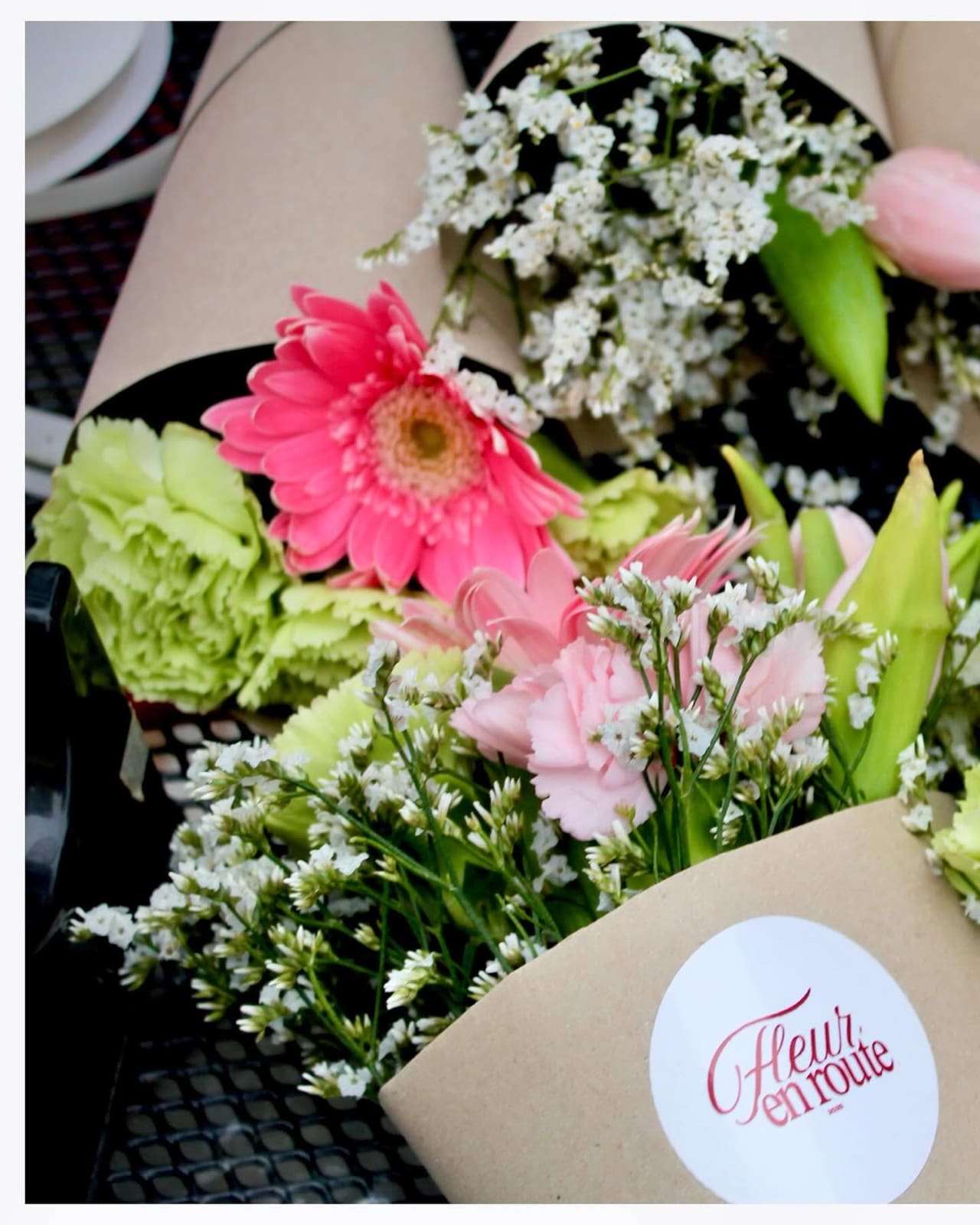 Kraft cone bouquets with logo stickers lined up on a café table