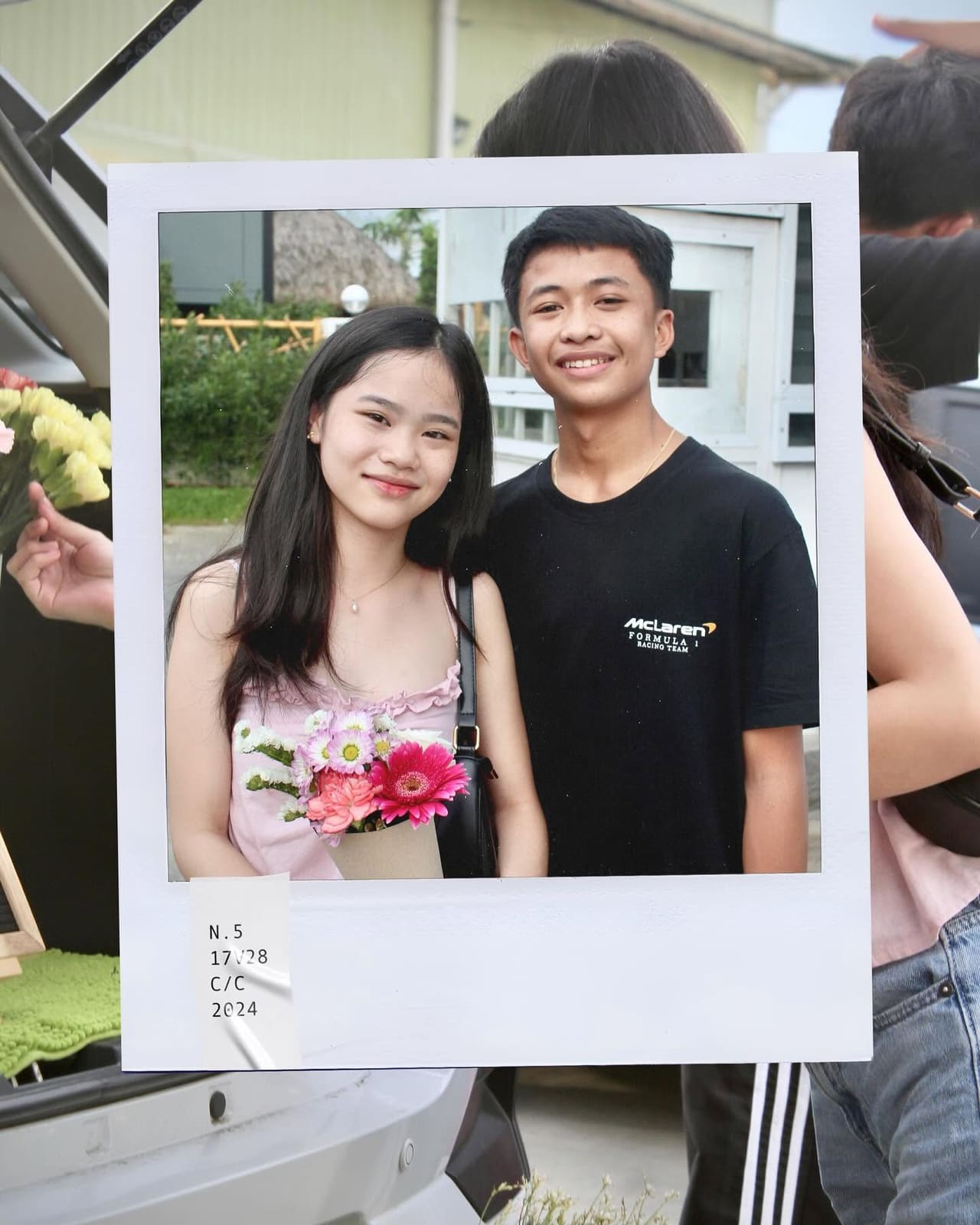 A couple's photo in a white polaroid frame, taken at the flower trunk
