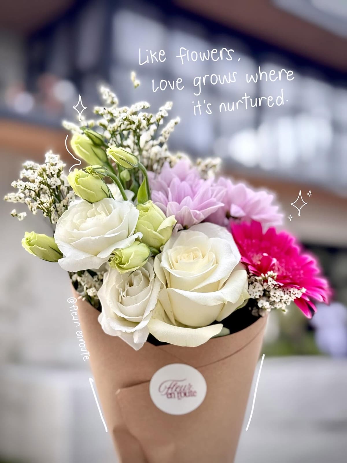 White roses, lisianthus, and a fuchsia gerbera in a kraft cone