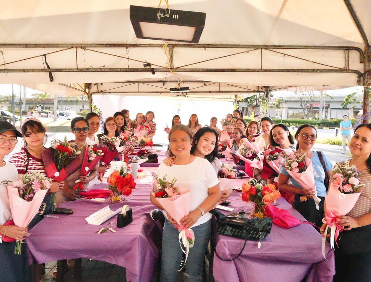 A long table of people proudly holding the bouquets they arranged themselves